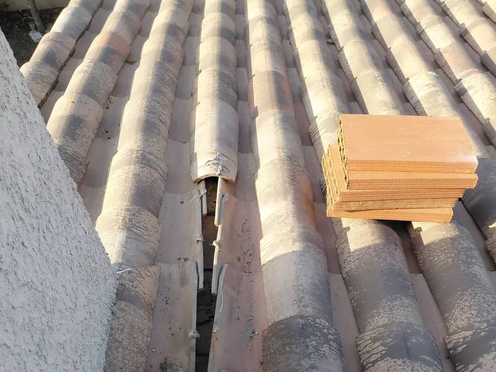 Pile de tuiles canal neuves posée sur un versant, à côté d’un rang de couvert déposé